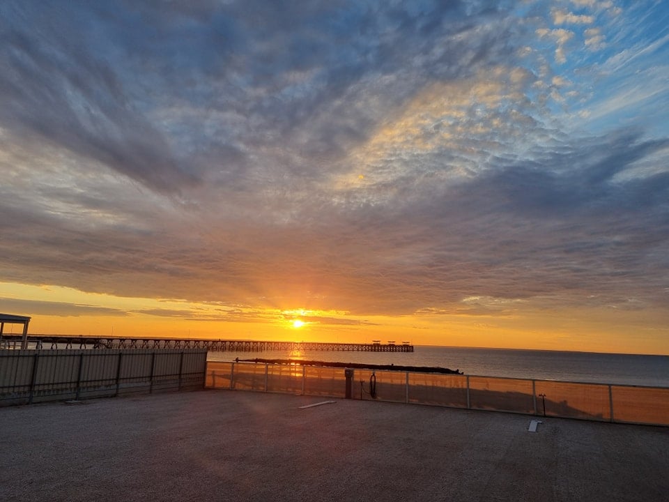 Sunset over ocean with pier in background