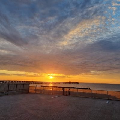 Sunset over beach with clouds and pier at Smoky Bay Caravan Park.