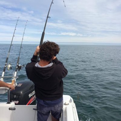 Person fishing from a boat on the ocean.