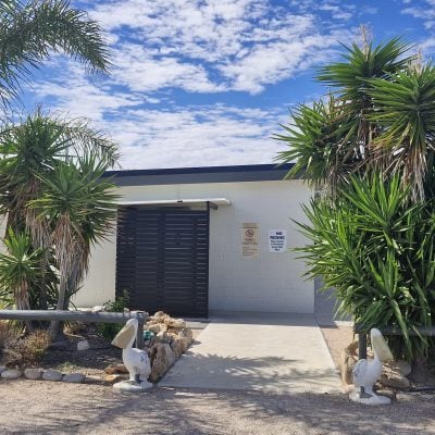 A modern amenities block with separate male and female sections is visible at the caravan park.