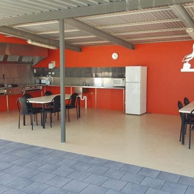 Outdoor camp kitchen at Smoky Bay Caravan Park with covered roof, picnic tables, and food preparation area